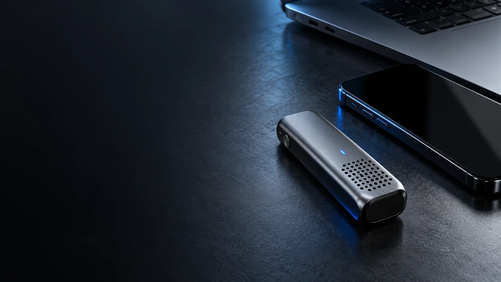 Enregistreur générique, téléphone et ordinateur sur une surface graphite éclairée en bleu.